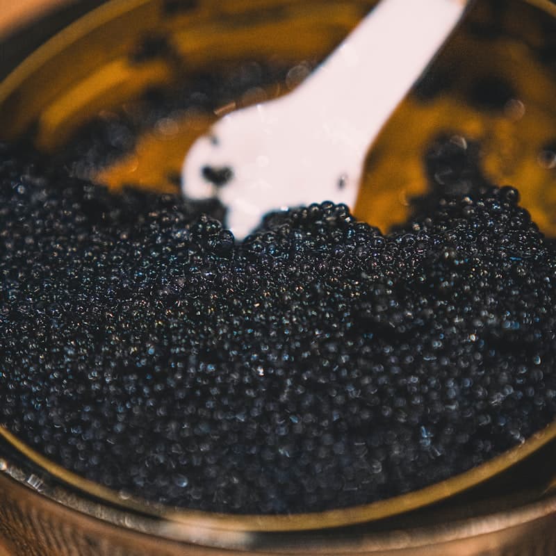 Black caviar in a golden bowl with a mother-of-pearl serving spoon
