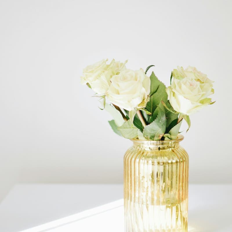White roses in an amber glass vase on a bright table