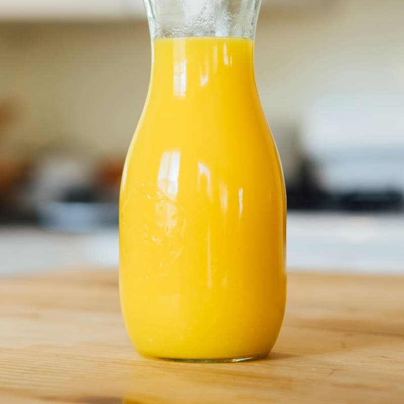 A glass carafe of freshly pressed orange juice on a light counter