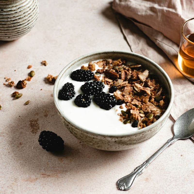 A bowl of Greek yogurt with granola and blackberries
